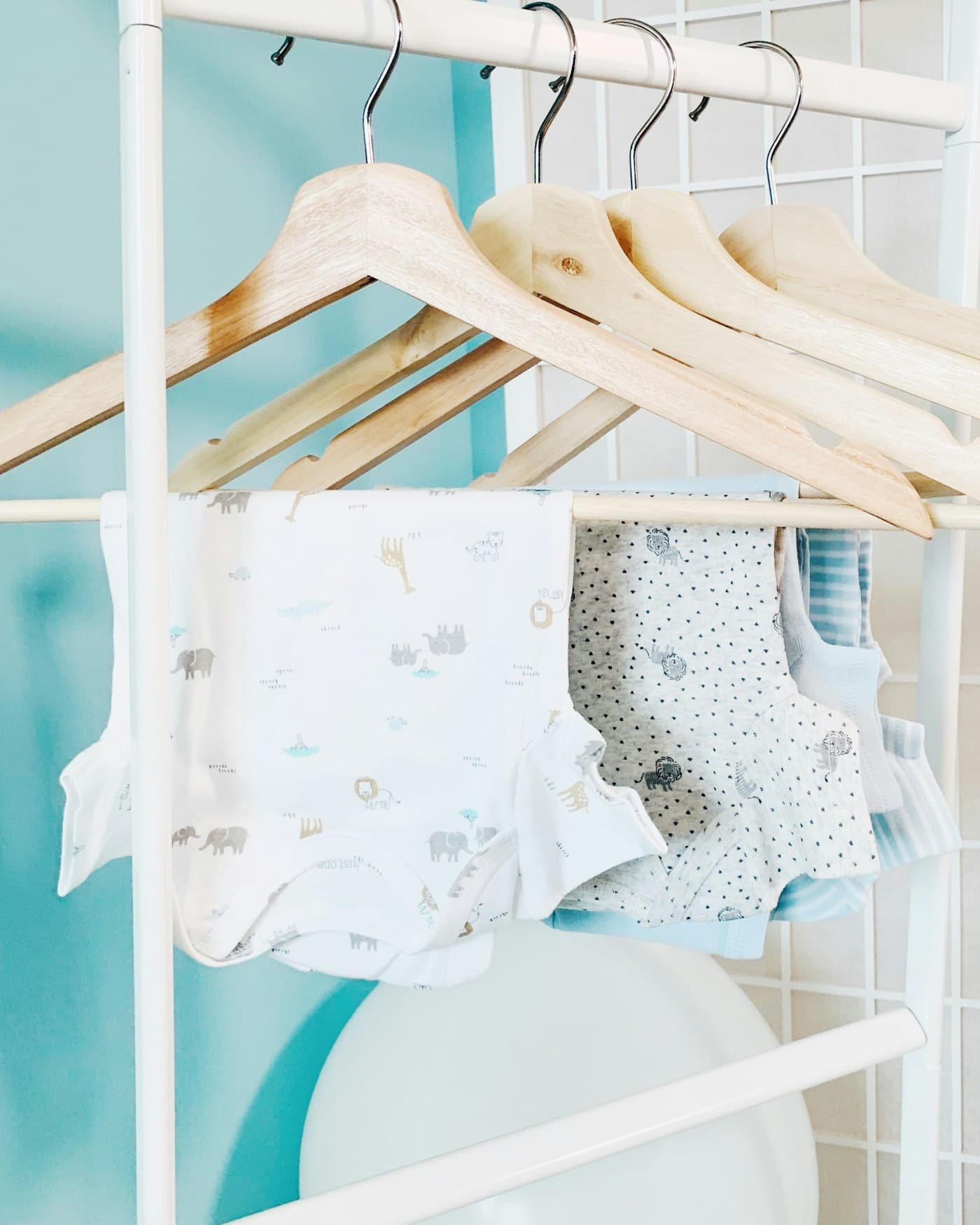 Printed baby bodysuits draped over wooden hangers